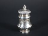 a silver salt shaker on a black surface with a black background