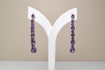Des boucles d'oreilles ornées d'améthorate et de perles d'améthorate sont présentées sur un présentoir blanc