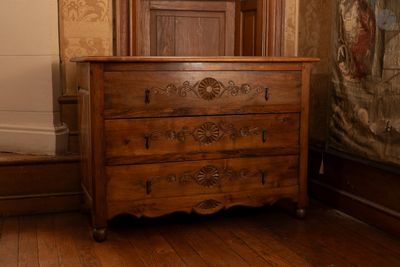 une commode dans une pièce où est accroché un tableau au mur