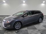 Une voiture grise est garée sur un sol à damier dans un garage.