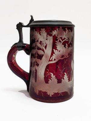 une tasse en verre rouge avec un couvercle noir et l'image d'un cerf