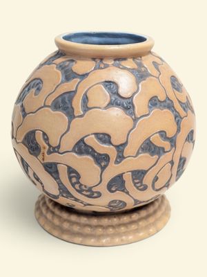 un vase bleu et beige posé sur un socle en bois
