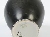 a black vase with a white lid sitting on a white surface