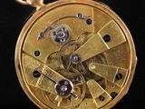 a close up of a gold pocket watch on a black background