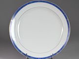 une assiette bleue et blanche bordée d'or, posée sur un socle