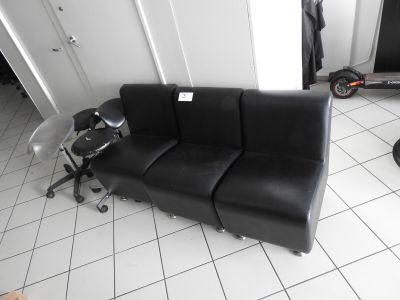 un canapé en cuir noir posé sur un sol carrelé dans une pièce