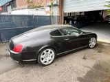 a picture of a black car parked in front of a garage