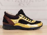 the black and gold sneakers are sitting on a wooden table