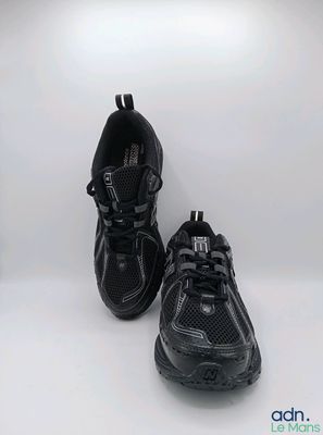 un gros plan sur une paire de chaussures de course noires posées sur une surface blanche