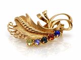 une image représentant une broche dorée ornée de pierres multicolores