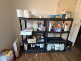 a black shelving in the corner of a room with a lot of supplies