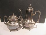 two silver teapots sitting next to each other on a table