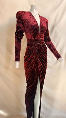 a red velvet dress with long sleeves and a slited skirt