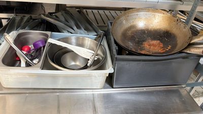 pots and pans are sitting on a metal shelf in a kitchen