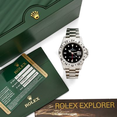 un gros plan d'une montre Rolex avec son coffret et ses papiers