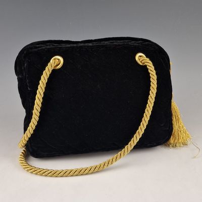un sac à main en velours noir muni d'une anse en corde dorée