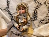 a doll that is sitting on a bed with a blanket
