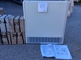 un réfrigérateur blanc posé à même le sol, à côté d'une pile de cartons