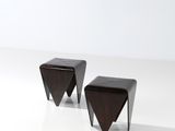 une paire de tabourets triangulaires en bois posés sur une surface blanche