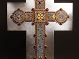 une croix en argent ornée de motifs multicolores, posée sur une table