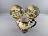a pitcher and two plates with a painting on it