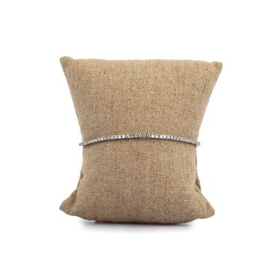 un bracelet en diamants posé sur un coussin, sur fond blanc