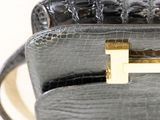a black purse with a gold handle on a white table