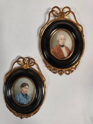 two framed portraits of a man and a woman are hanging on a wall