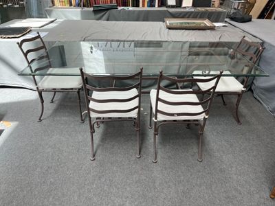 a glass dining table with four chairs and a bookcase
