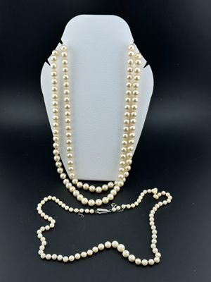 un ensemble composé d'un collier et d'un bracelet en perles blanches, présenté sur un présentoir pour mannequin