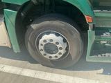 a green truck with a flat tire parked on the side of the road