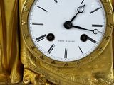 a gold clock with a statue on top of it