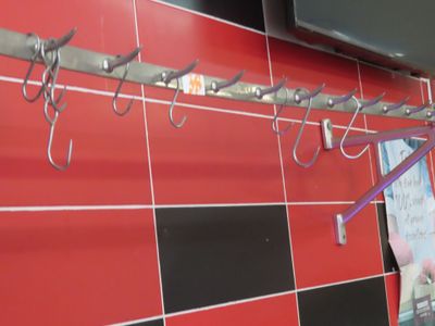 un mur recouvert de carreaux rouges sur lequel sont fixés plusieurs crochets