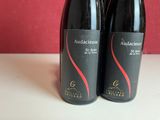 two bottles of red wine sitting on a table next to each other