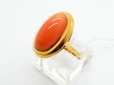 une image représentant une bague ornée d'une pierre rouge posée sur une surface transparente