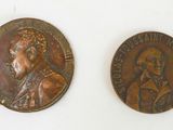 two bronze medallions of a man and a woman on a white surface