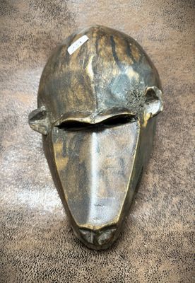 a close up of a metal mask on a brown surface