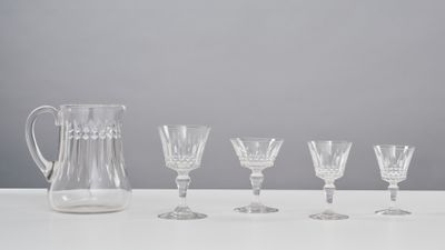 five wine glasses and a pitcher sitting on a table