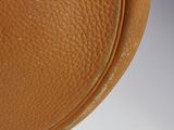 a close up of a brown leather bag on a white surface