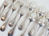 a lot of silver spoons and forks on a white table