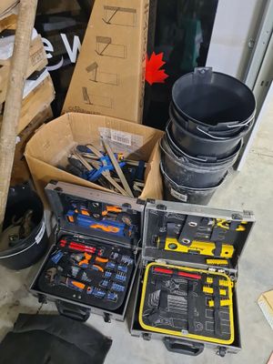 de nombreux outils dans une boîte posée par terre dans le garage