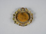 a close up of a gold and blue broochle on a white surface