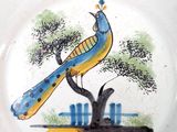 a plate with a bird painted on it and a tree in the background