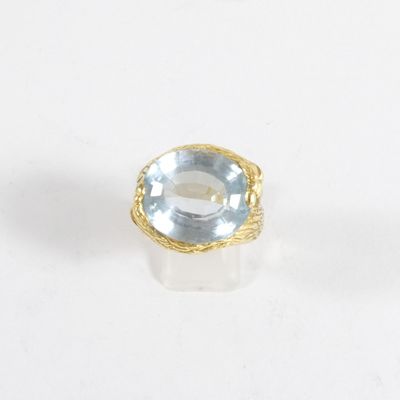 un gros plan d'une bague sertie d'une topaze bleue sur une surface blanche