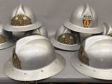 six white fire hats with gold decorations on them sitting on a table