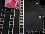 une échelle appuyée contre un mur sur lequel est accrochée une photo d'une femme