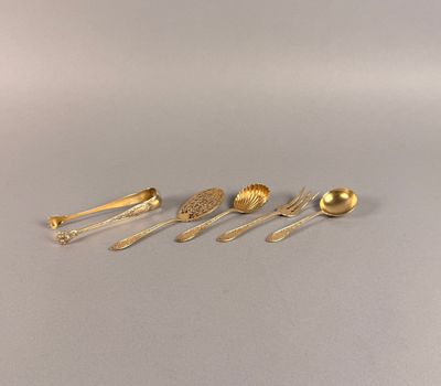 quatre cuillères en or et deux cuillères en argent posées sur un fond gris