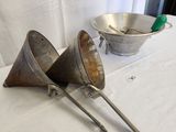 two metal funnels sitting on a table with a bowl in the background