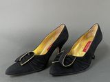 a pair of black shoes with a gold buckle on the heel
