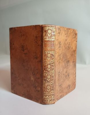 un vieux livre posé sur une table blanche à côté d'un mur blanc